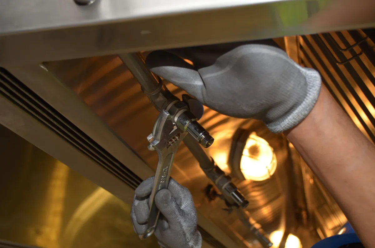 Mains gantées serrant un raccord de canalisation avec une clé