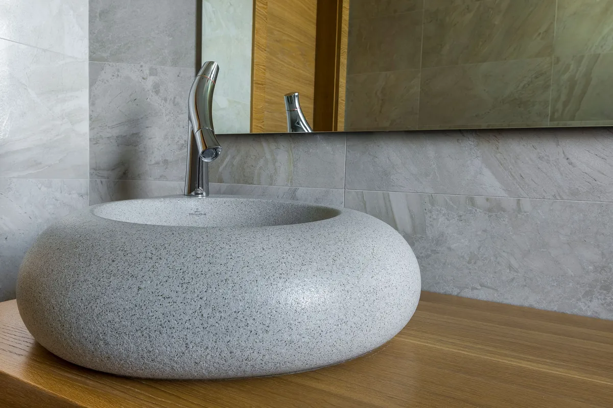 Vasque en pierre et robinet chromé dans une salle de bain